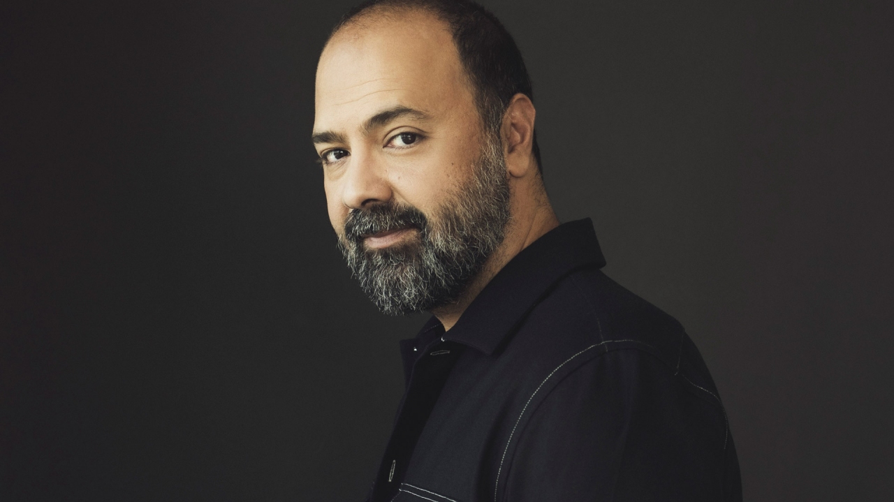 Mani Soleymanlou looks over his shoulder. He has dark hair, dark eyes, and a salt-and-pepper beard.